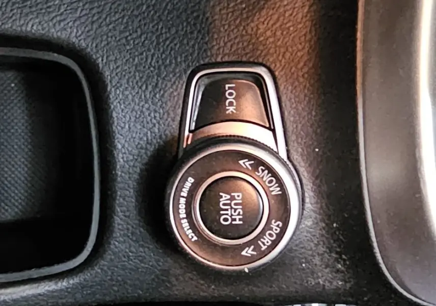 Gros plan sur la molette de sélection de mode de conduite et frein à main en cuir noir dans le Suzuki SX4 S-Cross 2020.