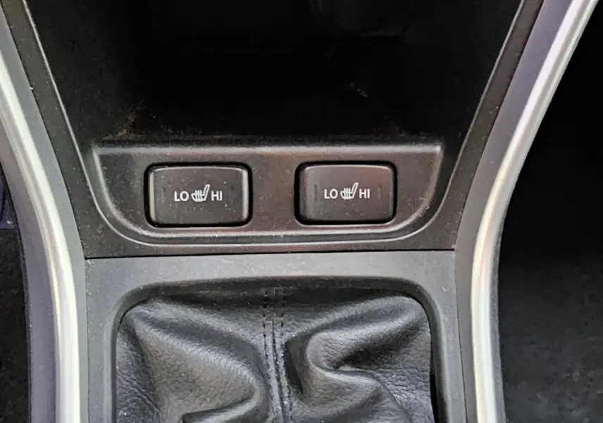 Gros plan sur les boutons de chauffage des sièges et le soufflet de levier de vitesse d'une Suzuki SX4 S-Cross gris 2020.
