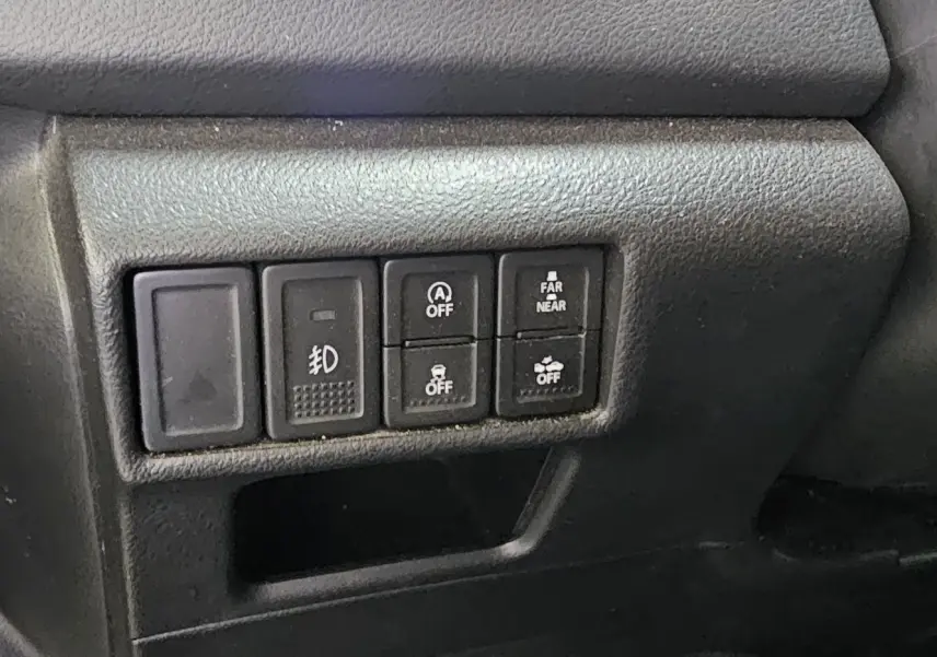 Gros plan sur les commandes de fonctions électroniques à gauche du volant du Suzuki SX4 S-Cross gris 2020.