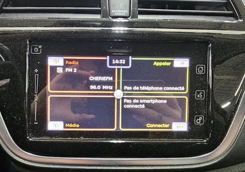 Écran tactile central du Suzuki SX4 S-Cross 2020 affichant radio FM et options de connexion smartphone, avec bouton start/stop rouge à gauche.