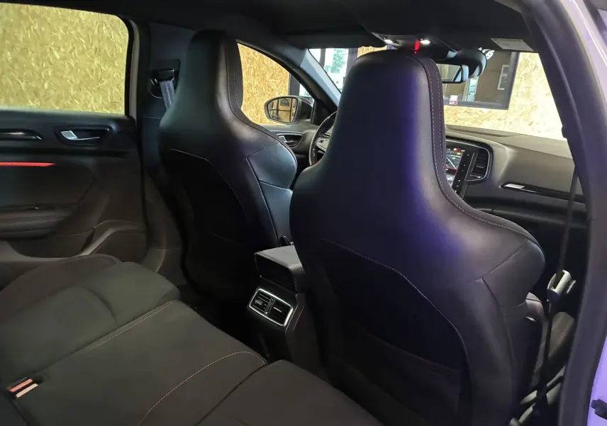 Vue intérieure arrière droite de la Renault Mégane IV RS 280 EDC6 avec sièges noirs et surpiqûres rouges.