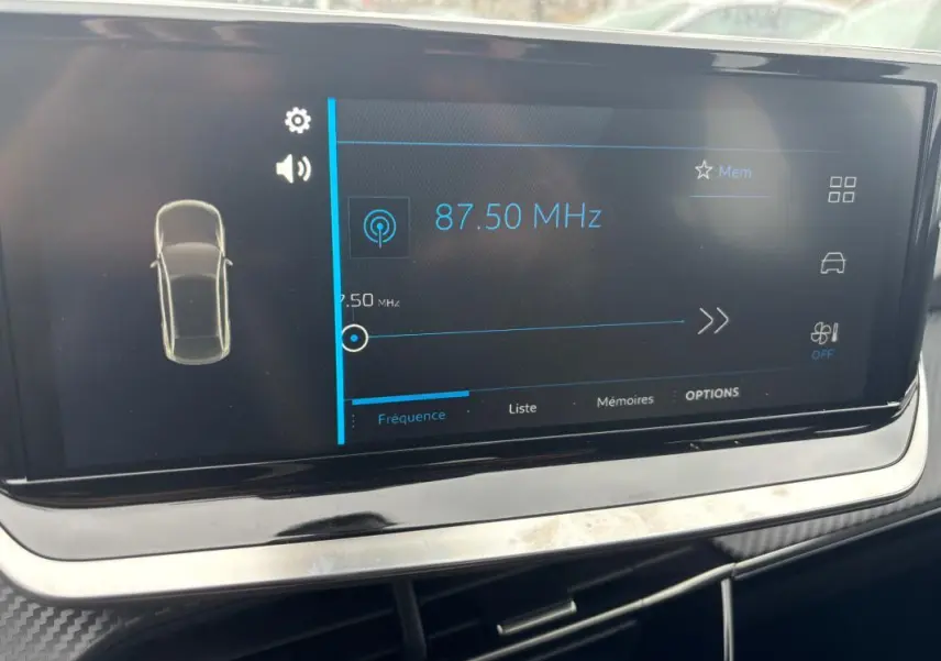 Écran tactile central de la Peugeot 208 Hybrid 100 e-DCS6 Style affichant la fréquence radio 87,50 MHz en intérieur.