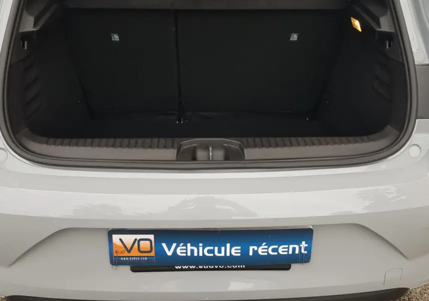 Vue arrière du coffre ouvert d'une Renault Clio gris clair, avec feux arrière et pare-chocs visibles.