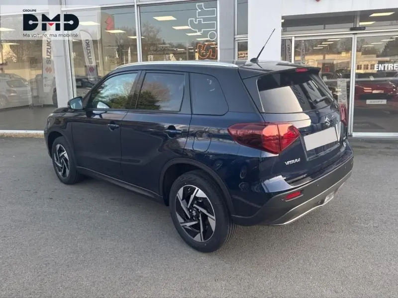 Suzuki Vitara 2026 bleu So'Color Sphere, vue 3/4 arrière droit, vitres surteintées et jantes alu distinctives.