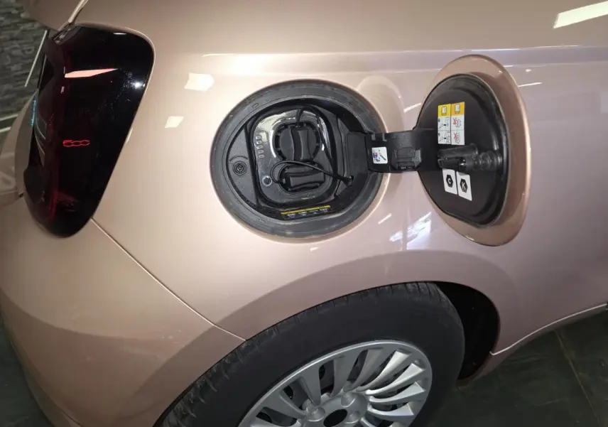 Vue arrière gauche d'une FIAT 500 Cabriolet électrique rose métallisée avec feu arrière LED et capote noire.