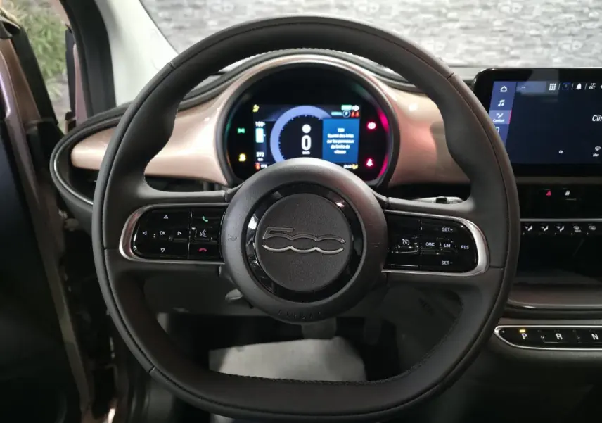 Vue centrée du volant noir Soft-Touch de la Fiat 500 Cabriolet électrique 2023 avec tableau de bord rose métallisé.