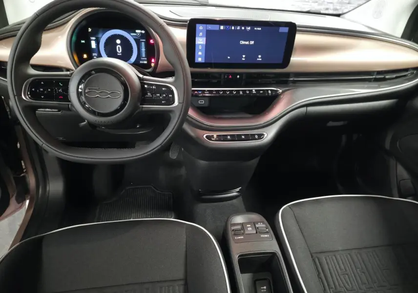 Vue intérieure avant de la Fiat 500 Cabriolet électrique 2023, planche de bord rose métallisé et volant noir Soft-Touch.