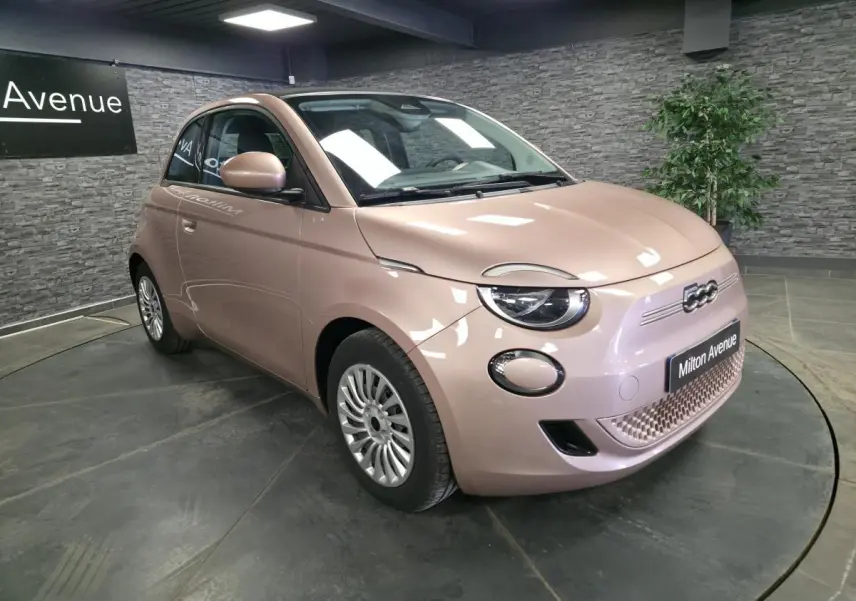 Vue 3/4 avant droite d'une Fiat 500 Cabriolet électrique rose métallisée avec jantes acier et capote noire fermée.