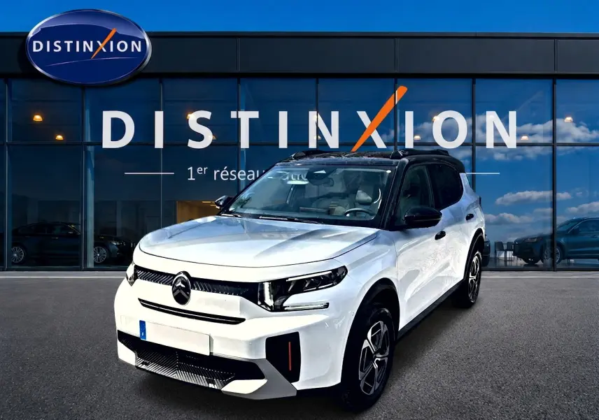 Vue 3/4 avant droite d'une Citroën C3 Aircross blanche avec toit noir et jantes alu devant un showroom Distinxion.
