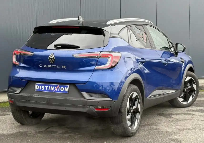Vue 3/4 arrière droite d'un Renault Captur 2025 bleu Iron et toit noir avec jantes alu 18 pouces diamantées noires.