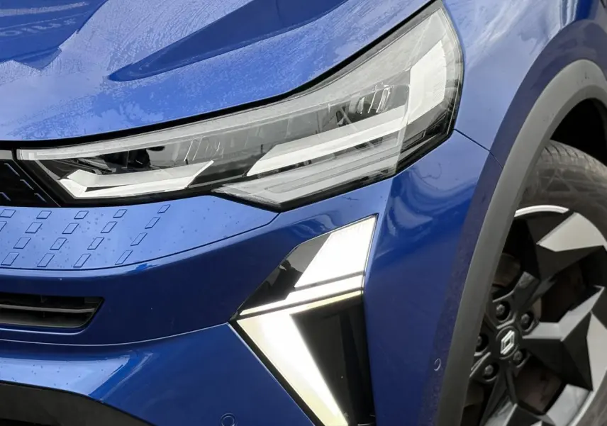 Gros plan sur l'avant droit du Renault Captur bleu Iron, mettant en valeur les phares LED et la jante alu diamantée noire.