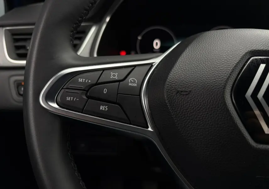 Gros plan sur le volant noir du Renault Captur 2025, mettant en valeur les commandes de régulateur de vitesse côté gauche.