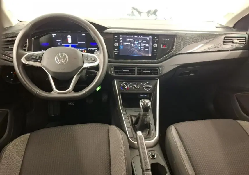 Intérieur avant de Volkswagen Polo gris clair 2023, volant cuir multifonction et console centrale avec boîte manuelle.