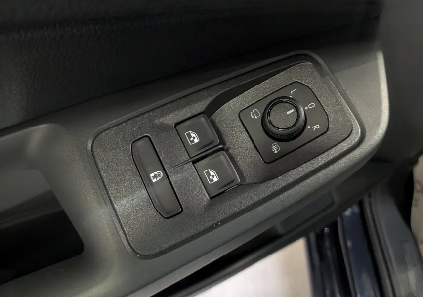 Gros plan sur les commandes de réglage des rétroviseurs et des vitres côté conducteur du Volkswagen Caddy noir 2025.