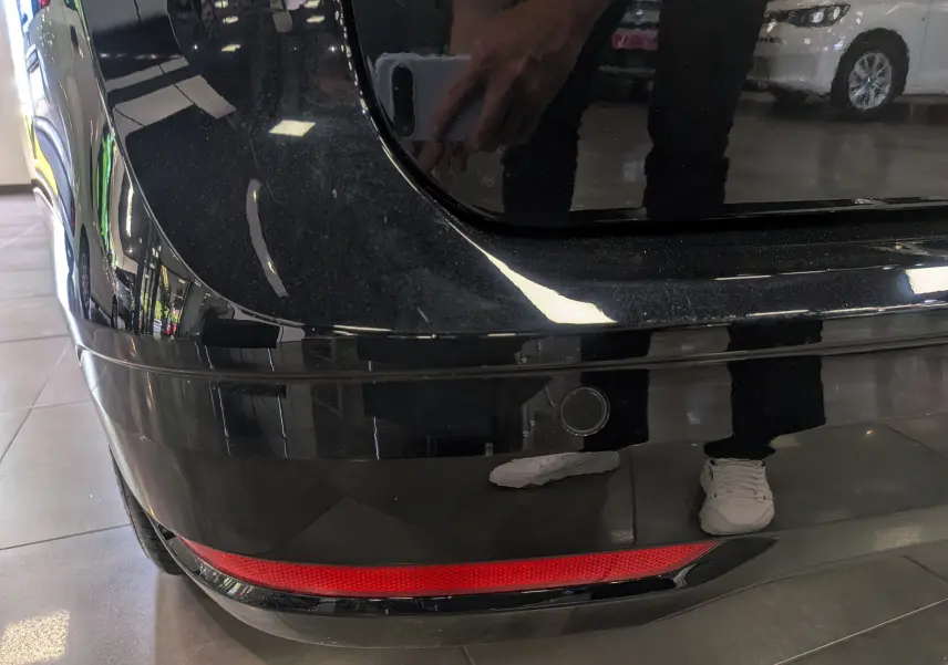 Gros plan sur le coin arrière gauche noir d’un Volkswagen Caddy 2.0 TDI, avec feu arrière rouge et capteur de recul visible.