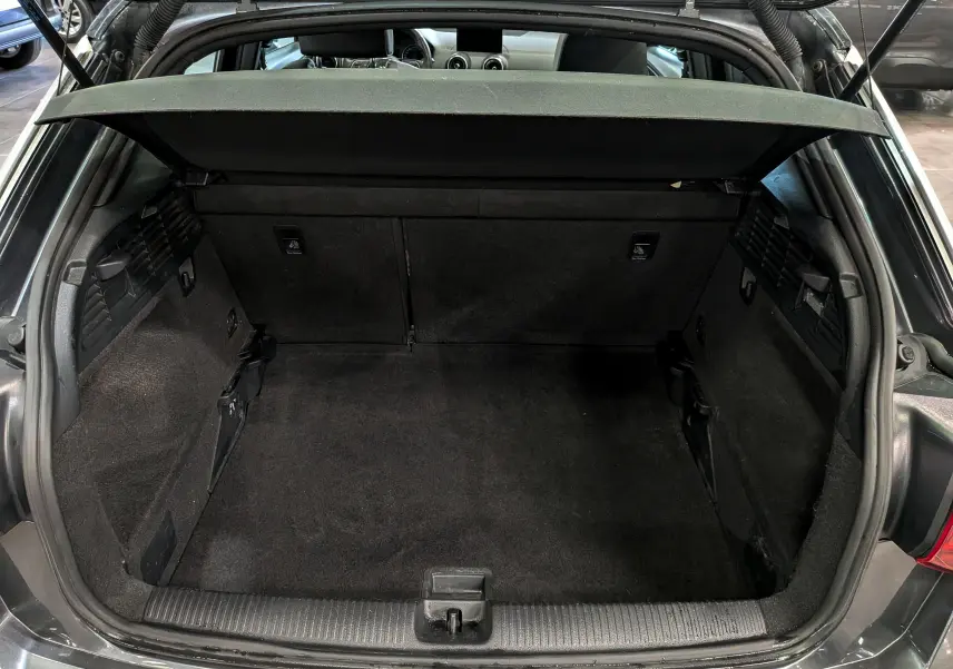 Coffre ouvert vu de l'arrière d'un Audi Q2 gris, montrant un espace de chargement propre et bien agencé.