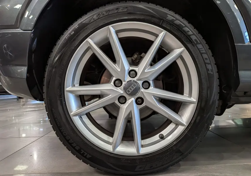 Gros plan sur la roue avant droite d’un Audi Q2 gris 2017, mettant en valeur la jante alliage 18 pouces à 5 doubles branches.