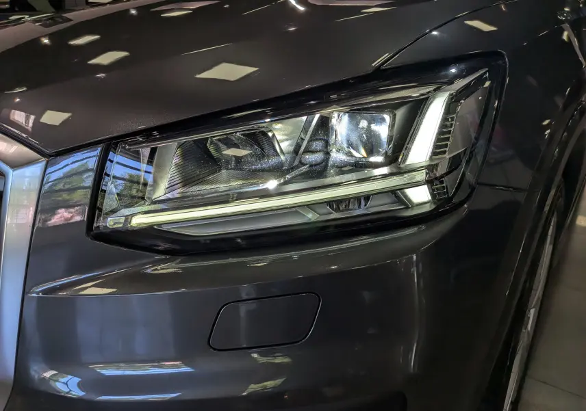 Gros plan sur le phare avant droit gris d’un Audi Q2 1.4 TFSI S-Line de 2017 avec éclairage LED distinctif.