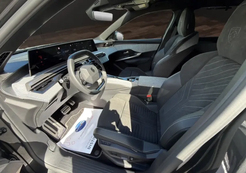 Vue intérieure côté conducteur du Peugeot 5008 gris foncé, avec sièges Alcantara et tableau de bord numérique large.