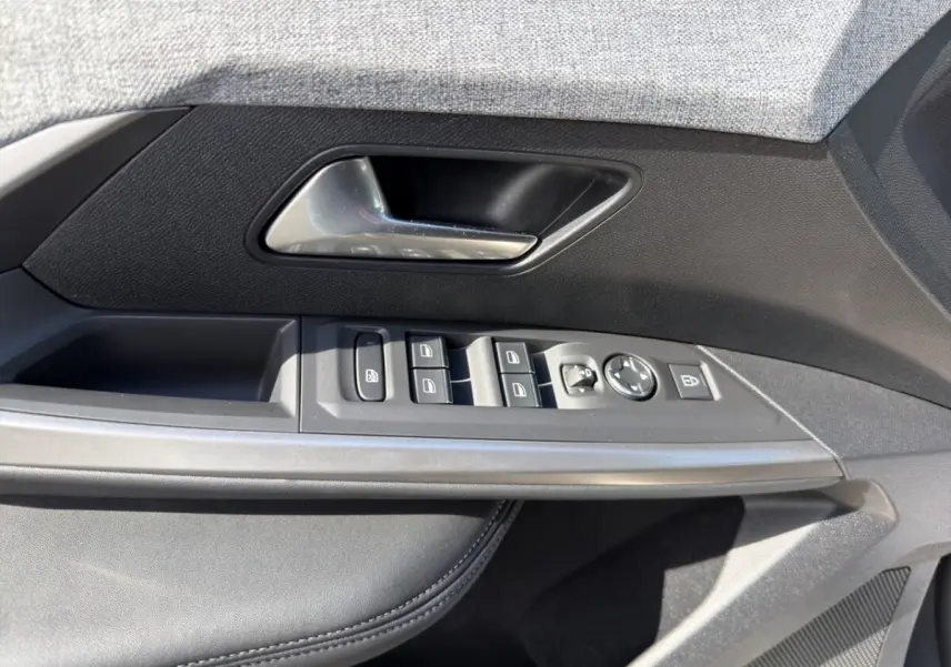 Gros plan sur la porte côté conducteur du Peugeot 5008 gris foncé, montrant les commandes des vitres et rétroviseurs.
