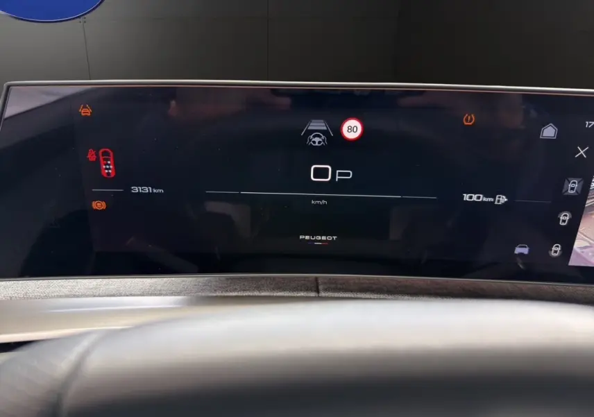 Tableau de bord numérique du Peugeot 5008 gris foncé, affichage multifonctions avec vitesse et alertes visibles.
