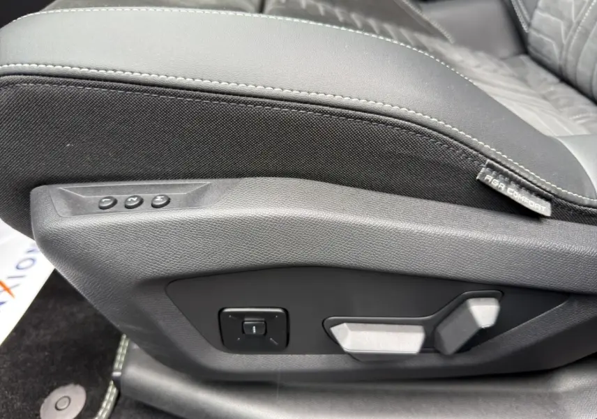Gros plan sur la commande de réglage électrique du siège avant en cuir et tissu noir du Peugeot 5008 gris foncé.