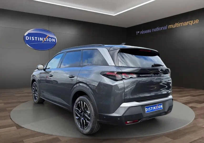 Peugeot 5008 gris foncé vue 3/4 arrière droit, avec jantes noires et toit noir brillant en showroom.