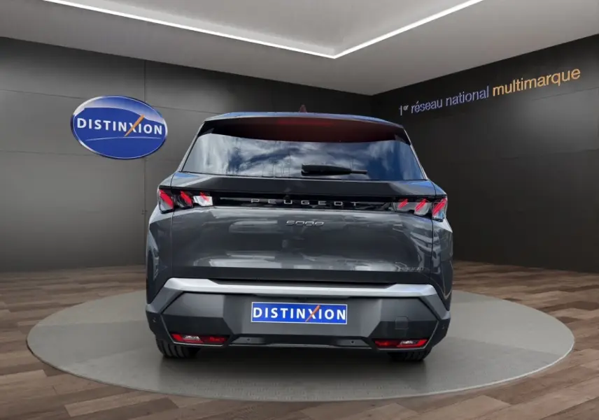 Vue arrière d'un Peugeot 5008 gris foncé hybride 2025 avec feux LED et logo distinctif sur fond showroom.