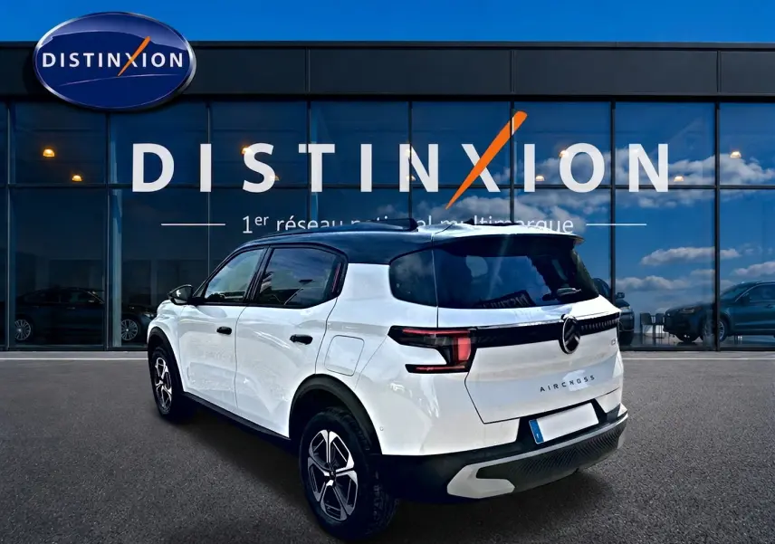 Vue 3/4 arrière droite d'un Citroën C3 Aircross blanc avec toit noir et feux arrière LED, devant une vitrine Distinxion.