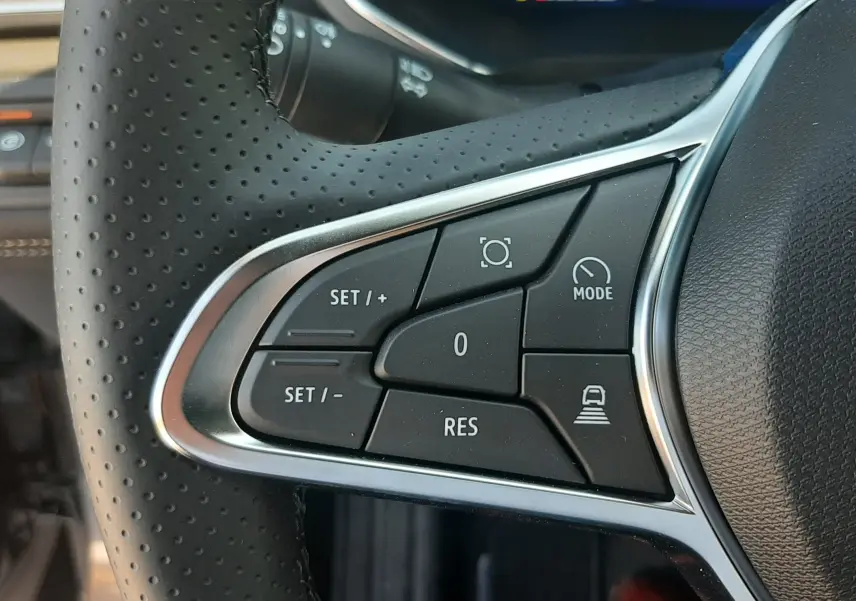 Gros plan sur les commandes de régulateur de vitesse au volant en cuir perforé noir du Renault Symbioz hybride.