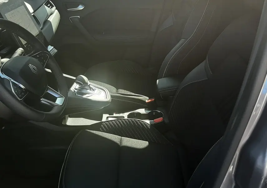 Intérieur noir de la Renault Symbioz E-Tech, vue côté gauche montrant sièges avant et console centrale avec levier de vitesse.