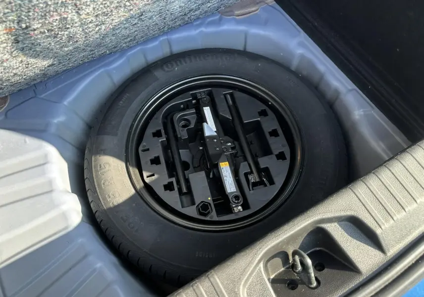 Roue de secours tôle avec outils de changement dans le coffre d'une Renault Clio TCE 90 Techno Bleu Iron 2025.