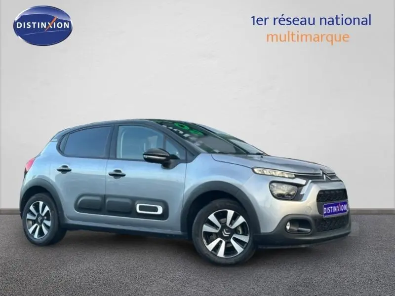 Citroën C3 gris vue 3/4 avant droit, avec protections latérales noires et jantes bi-ton, sur fond neutre.