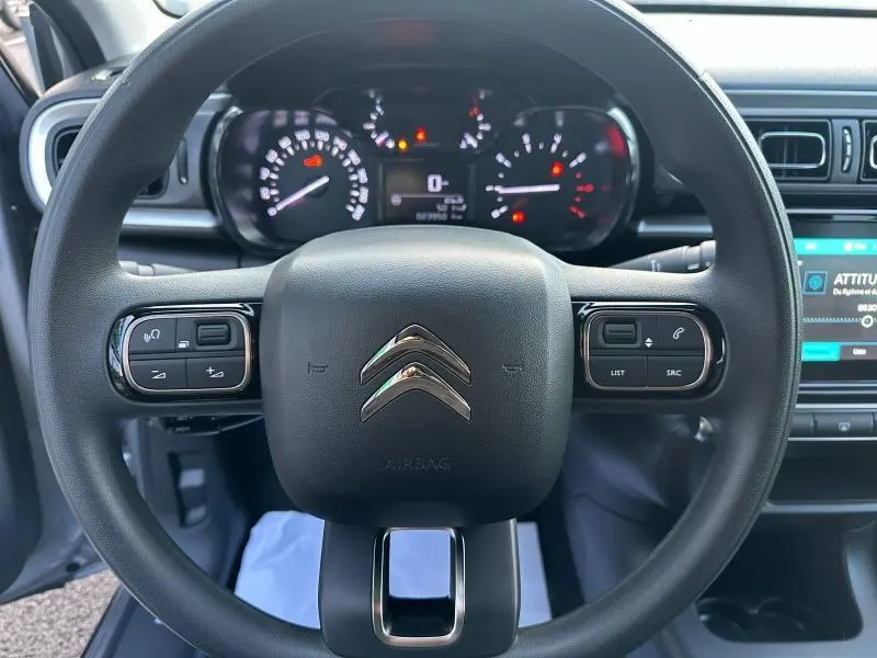 Vue frontale du volant gris du Citroën C3 2023 avec commandes intégrées et tableau de bord numérique allumé.