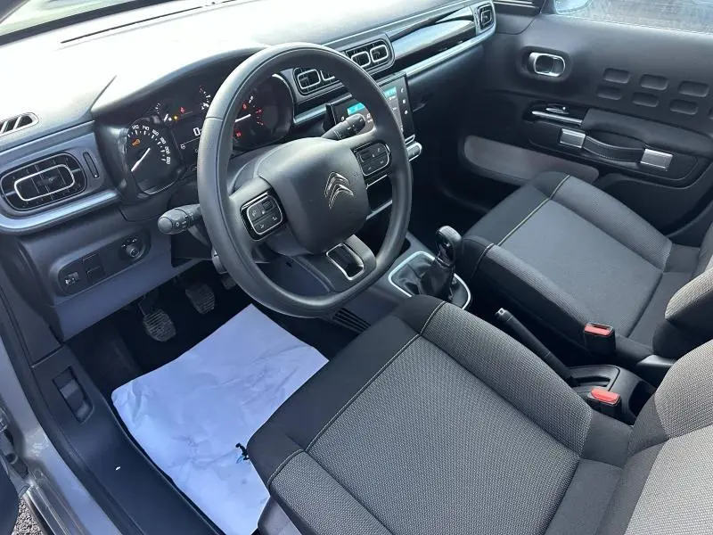 Vue intérieure côté conducteur de la Citroën C3 gris 2023, avec volant multifonction et boîte manuelle visible.