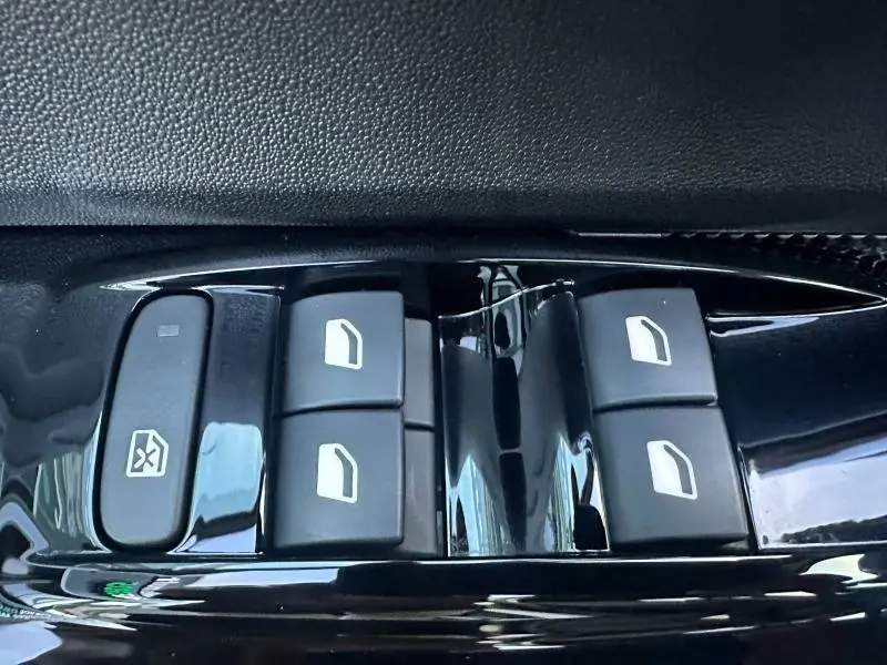 Gros plan sur les commandes de lève-vitres électriques en plastique noir brillant du Citroën C3 gris 2023.
