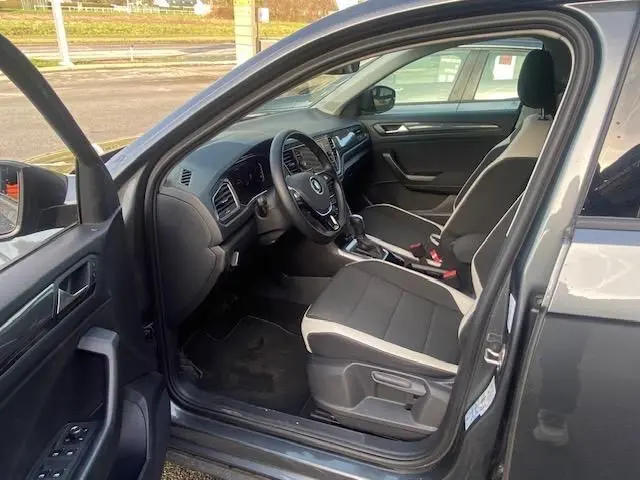 Intérieur côté conducteur du Volkswagen T-Roc gris Indium 2021, avec tableau de bord et sièges en tissu noir et beige.