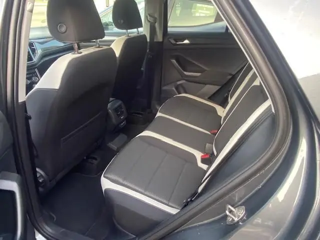 Vue intérieure arrière droite du Volkswagen T-Roc gris Indium 2021, montrant les sièges arrière en tissu bicolore et l'habitacle spacieux.