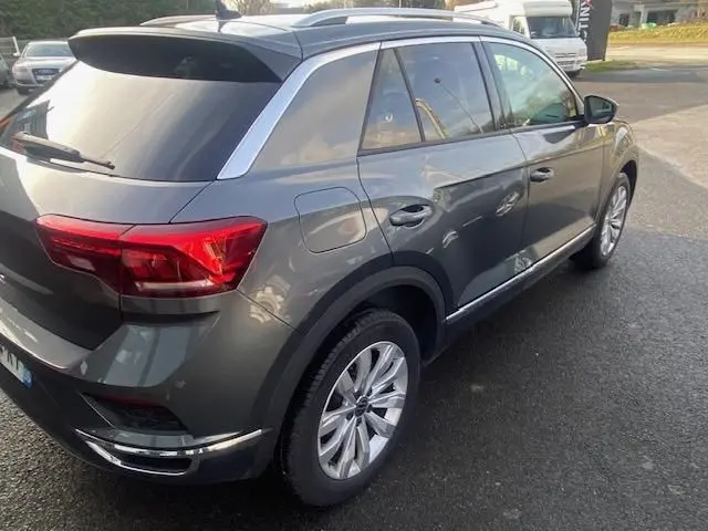 Vue 3/4 arrière droite d’un Volkswagen T-Roc gris Indium 2021 avec jantes alliage et vitres teintées.