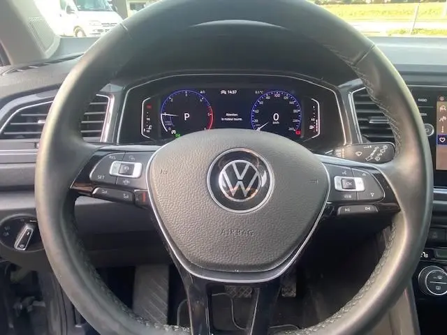 Vue centrée sur le volant cuir du Volkswagen T-Roc gris Indium 2021, avec tableau de bord numérique et commandes intégrées.