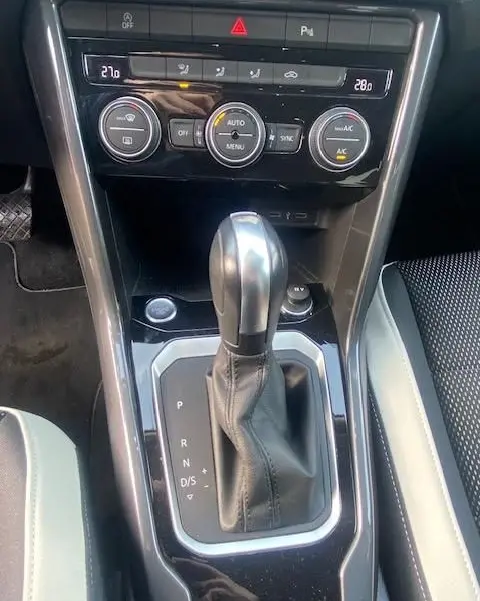 Gros plan sur la console centrale du Volkswagen T-Roc TDI 150 DSG 7 Carat, avec levier de vitesse automatique et commandes climatisation.