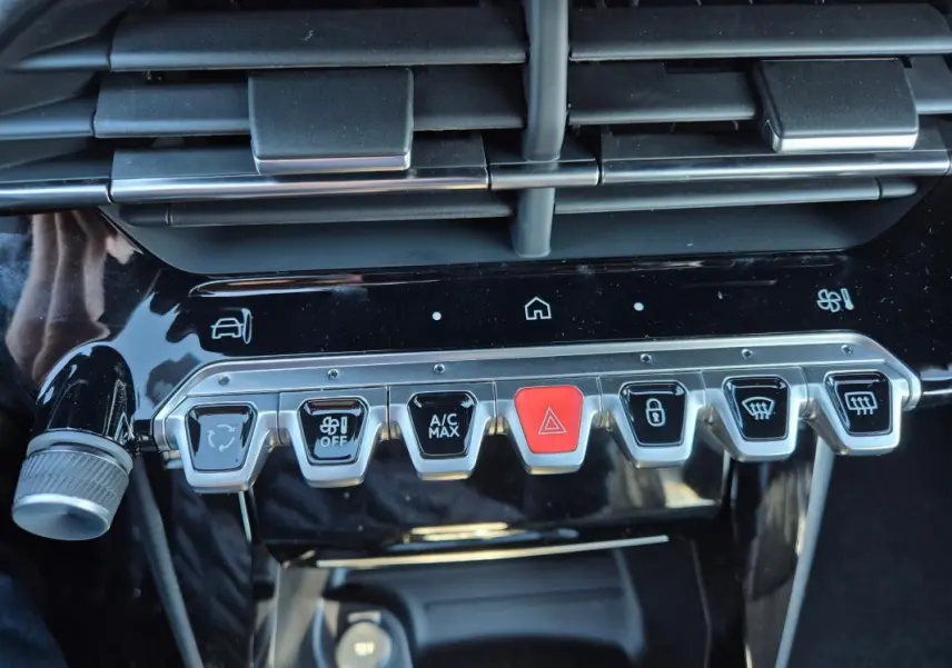 Gros plan sur la rangée de boutons de commande du tableau de bord noir brillant du Peugeot 208 Hybrid blanc.