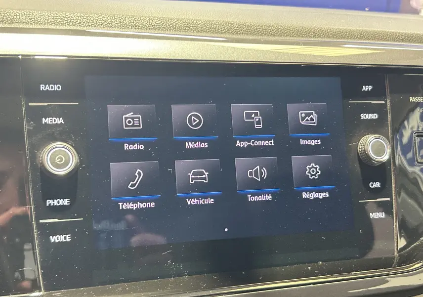 Écran tactile central du tableau de bord de la Volkswagen Polo gris, affichant le menu multimédia avec options connectées.
