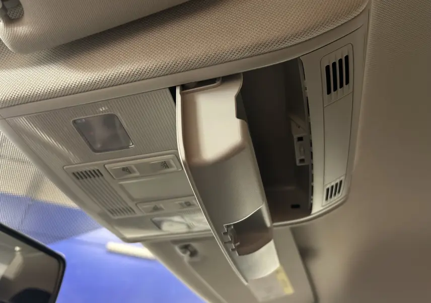 Vue intérieure en gros plan du compartiment à lunettes ouvert sur le plafond beige d'une Volkswagen Polo gris 2018.