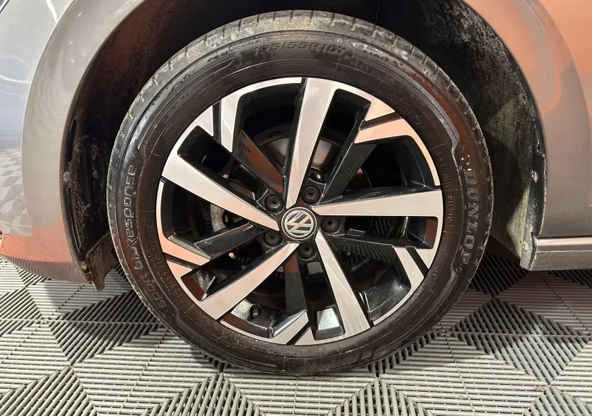 Gros plan sur la roue avant droite d'une Volkswagen Polo gris avec jante alliage bicolore et logo VW central.
