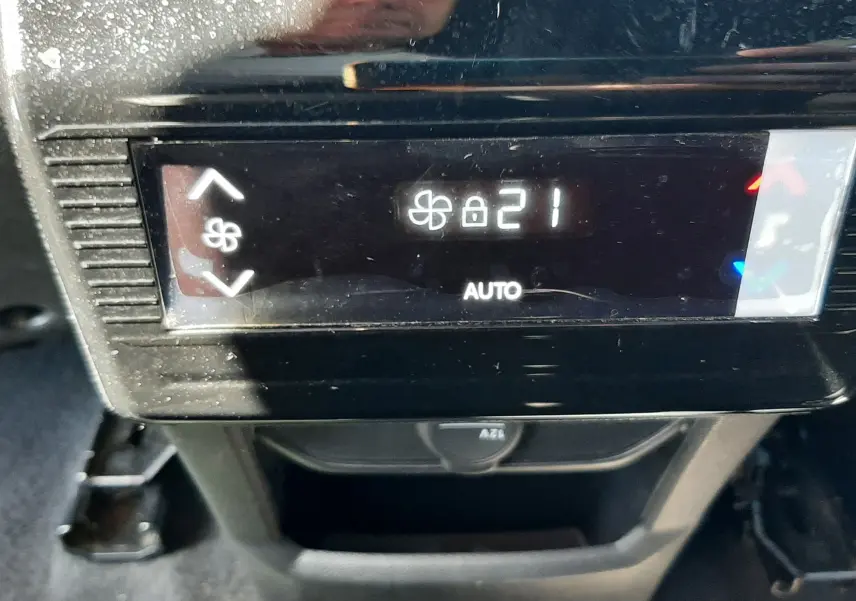 Gros plan sur l'écran de climatisation automatique réglé à 21°C dans un Peugeot 5008 blanc Okenite 2025 hybride.