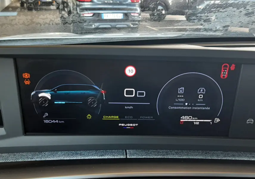 Tableau de bord numérique du Peugeot 5008 Hybrid blanc, affichant consommation et autonomie, vue intérieure frontale.