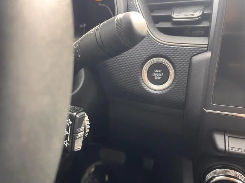 Gros plan sur le bouton Start Engine Stop noir entouré de chrome, côté gauche du tableau de bord du Renault Arkana blanc perle.