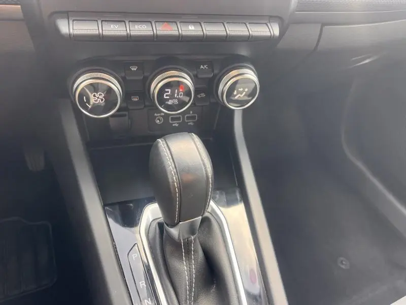 Gros plan sur la console centrale du Renault Arkana blanc perle, avec levier de vitesse cuir et commandes climatiques.