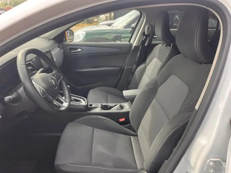 Vue intérieure côté conducteur du Renault Arkana blanc perle, sièges sport en cuir/suédine noir avec surpiqûres blanches.